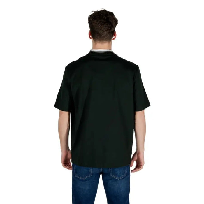 Man in dark green short-sleeved shirt and blue jeans showcasing Armani Exchange T Shirt
