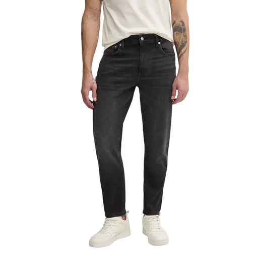 Man wearing dark wash jeans and white sneakers showcasing modern men’s fashion