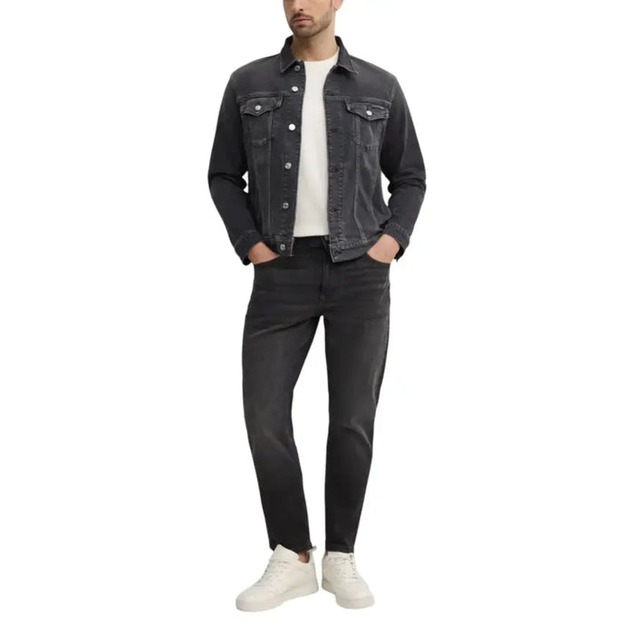 Man wearing dark wash denim jacket and jeans with white sneakers