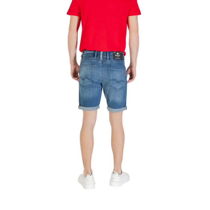 Man wearing denim shorts, white sneakers, and a red T-shirt in a product display