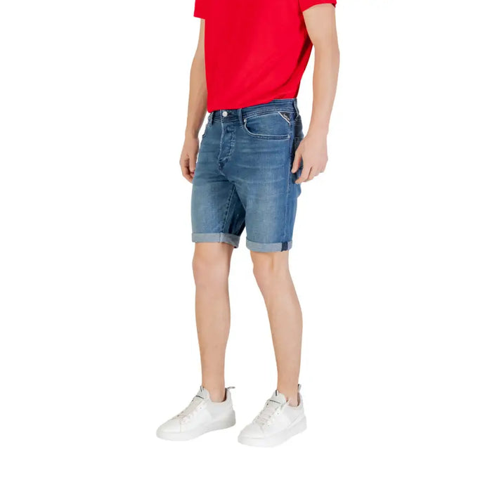Male model wearing denim shorts and white sneakers, styled with a red T-shirt