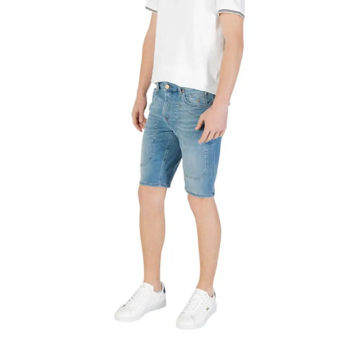 Man wearing denim shorts and white sneakers showcasing men’s denim shorts and white sneakers product