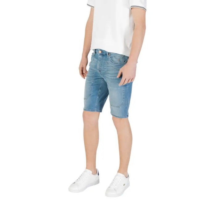 Man wearing denim shorts and white sneakers showcasing men’s denim shorts and white sneakers product