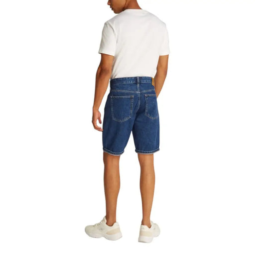 Man modeling white T-shirt and blue denim shorts with cuffed hems