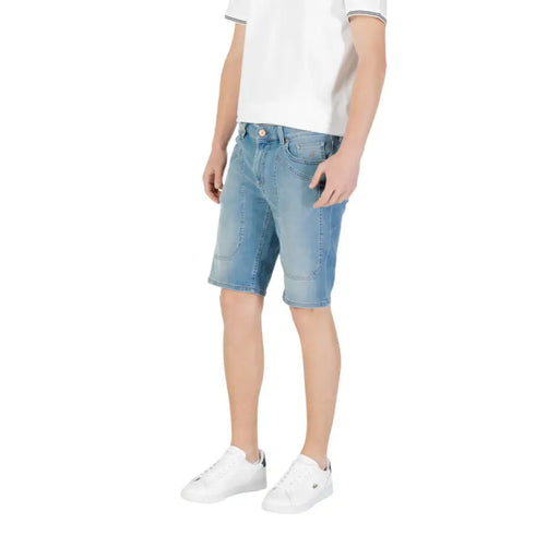 Man wearing light blue denim shorts paired with white sneakers for a casual look