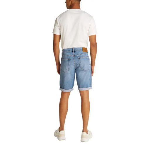 Man wearing light blue denim shorts and a white T-shirt in a product display
