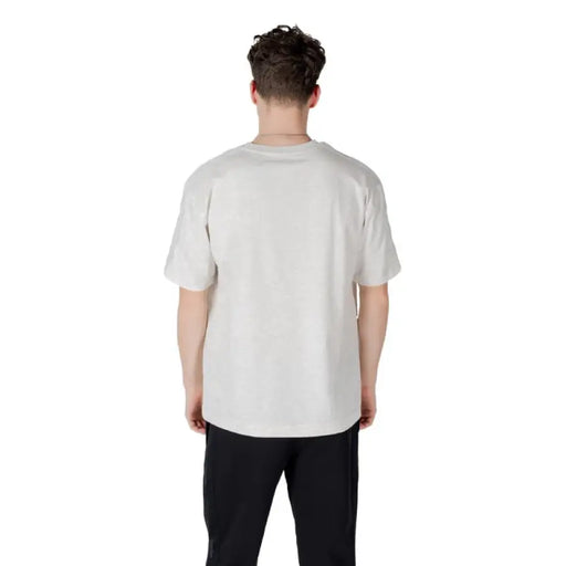 Man wearing a light-colored T-shirt and black pants presenting casual men’s fashion
