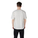 Man wearing a light-colored T-shirt and black pants presenting casual men’s fashion