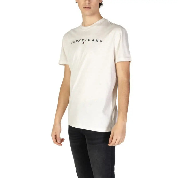 Man wearing a light-colored Tommy Jeans short sleeve T shirt and dark jeans