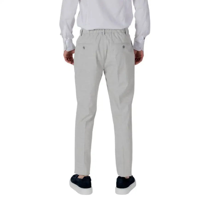 Man wearing light gray pants and dark blue sneakers in Men White Shirt and Gray Pants Apparel