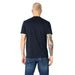 Man in navy blue Armani Exchange T-shirt and jeans, showcasing a tattoo sleeve on his right arm