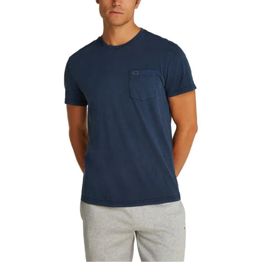 Man in a navy T shirt and gray pants, standing confidently