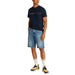 Man wearing a navy Tommy Hilfiger T-Shirt and denim shorts for casual style