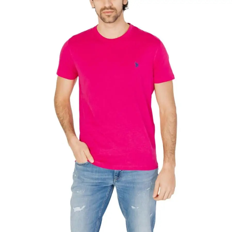 Man wearing U.S. Polo Assn. men t-shirt in pink, jeans, showcasing apparel accessories.