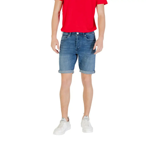 Man wearing a red T-shirt and denim shorts with white sneakers for casual style