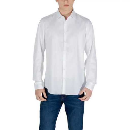 Man in white dress shirt and blue jeans showcasing Calvin Klein White Long Sleeve Shirt for Men