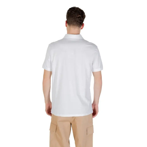 Man wearing a white polo shirt and khaki cargo pants standing outdoors