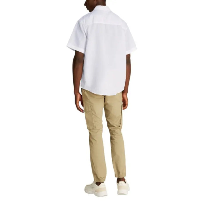 Man wearing a white short-sleeved button-down shirt and khaki pants