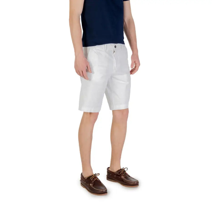 Man wearing white chino shorts and brown boat shoes in a stylish summer outfit