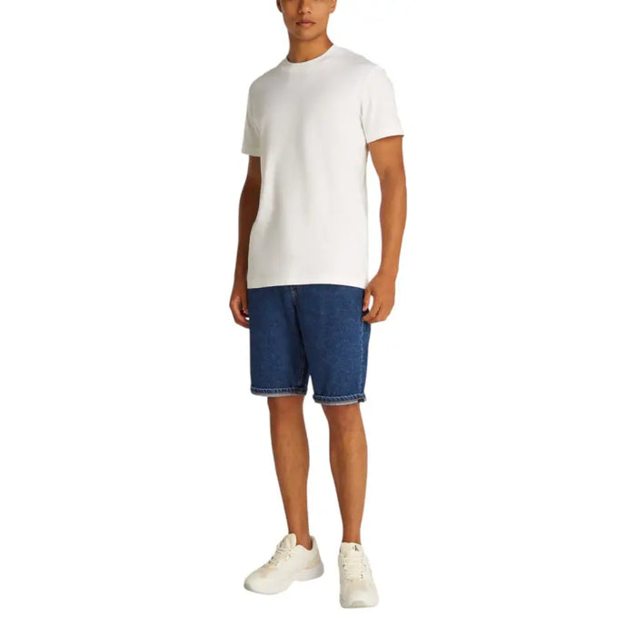 Man wearing a white T-shirt and blue denim shorts with cuffed hems