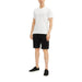 Male model wearing a white T-shirt and cuffed black denim shorts for a casual look