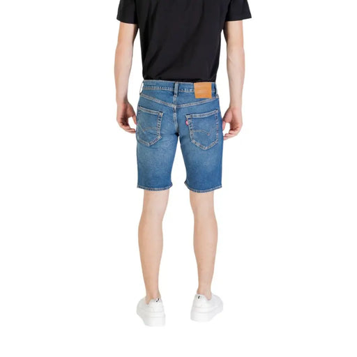 Short en jean bleu pour homme, vue de dos montrant la coupe classique à cinq poches et l'écusson de la marque en cuir beige sur la ceinture.