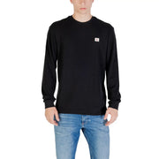 Man wearing a black long-sleeved shirt paired with blue jeans