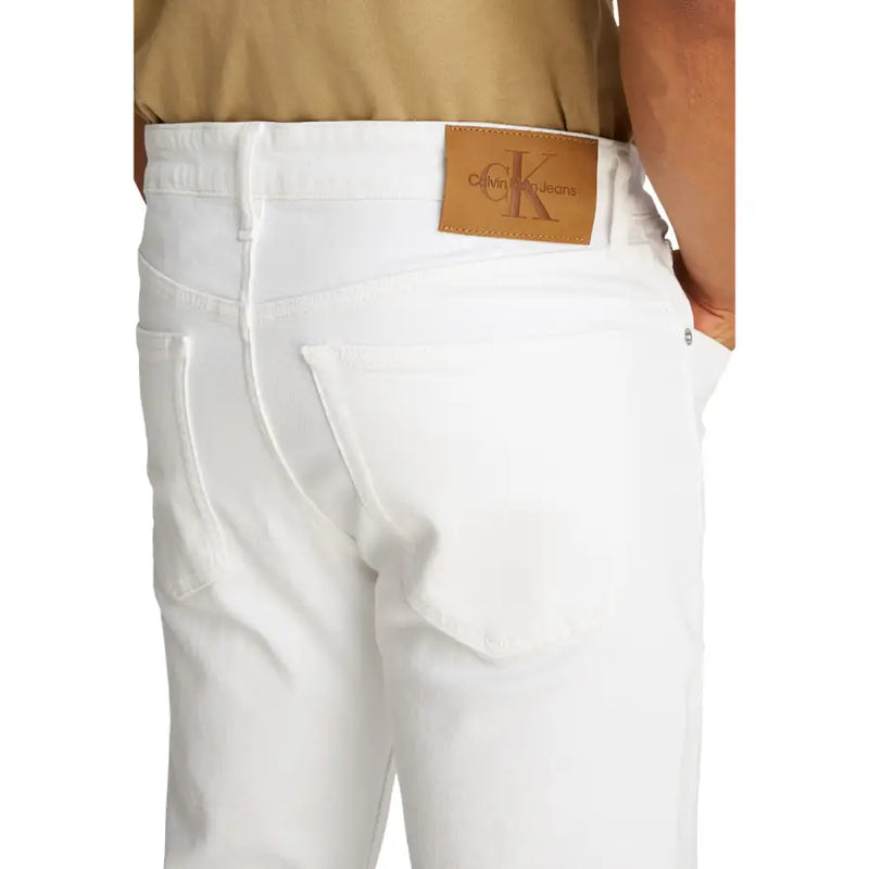 Men’s white denim jeans showing the back side with a tan leather Calvin Klein brand patch on the waistband