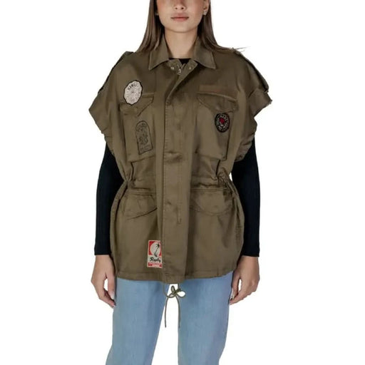 Military-style olive vest with patches over black long-sleeve top and Replay shirt
