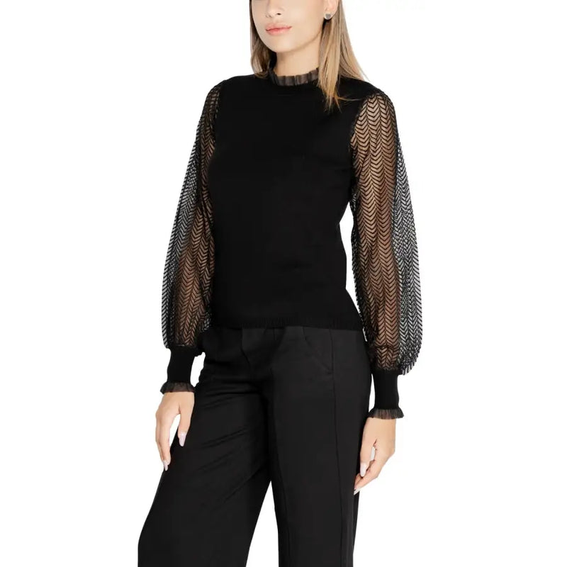 Black long-sleeve knit top with sheer patterned puff sleeves and ruffled mock neck