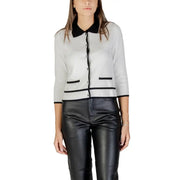 Women’s white cardigan with black trim and buttons paired with black faux leather pants