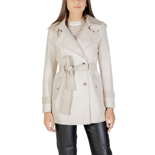 Beige double-breasted trench coat with belt and wide lapels over white lace top and black pants