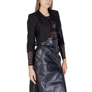Morgan De Toi Gilet noir pour femme à manches 3/4 orné de dentelle, porté avec une jupe noire en similicuir.