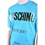 bleu clair Moschino hommes t-shirt avec un noir et argent brillant audacieux Moschino lettrage avec texte couture plus petit en dessous