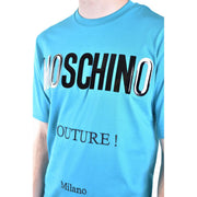 Light blue Moschino men t-shirt featuring bold black and silver glossy Moschino lettering with smaller couture text below