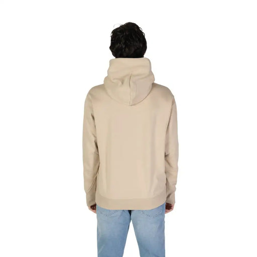 Person modeling beige New Balance men sweatshirt with turtleneck and light wash jeans