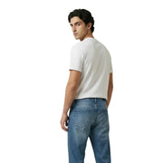 Un homme portant un simple t-shirt blanc à manches courtes en coton t-shirt et jeans en denim bleu délavé moyen par New Balance