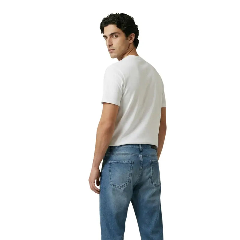 Un homme portant un simple t-shirt blanc à manches courtes en coton t-shirt et jeans en denim bleu délavé moyen par New Balance