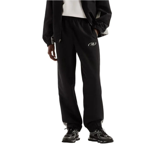 New Balance Pantalon de jogging homme noir en polyester, idéal pour l'automne et l'hiver, avec logo blanc discret et finitions grises aux chevilles.