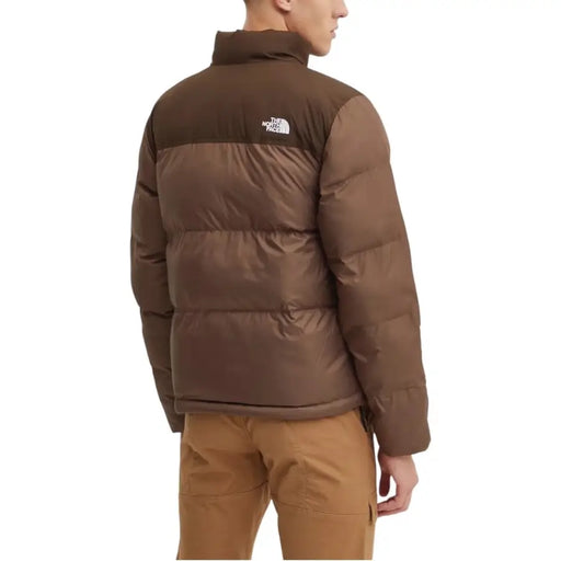 Brown puffer jacket with high collar and the north face logo on the back.