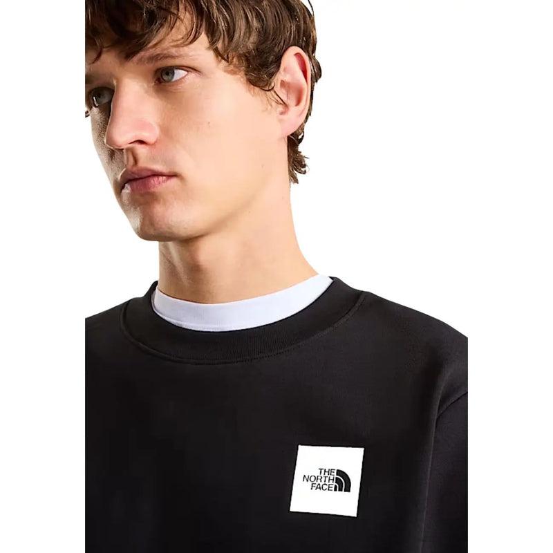 Sweat-shirt The North Face pour homme, en coton noir, coupe classique, avec un logo rectangulaire blanc sur la poitrine.