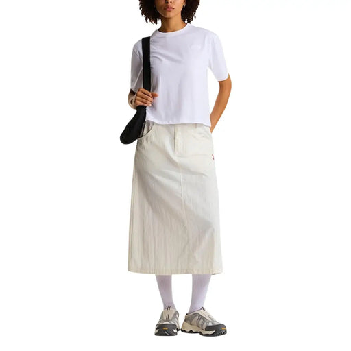 Une jupe crème mi-cuisse à la coupe décontractée et plissée, associée à un t-shirt blanc en coton mélangé pour femme de la marque The North Face.