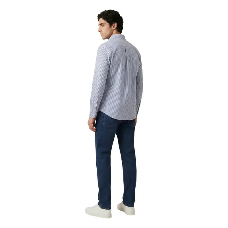 Un homme portant un Only & Sons Chemise homme à rayures verticales bleu clair et blanches, portée avec un jean en denim foncé.