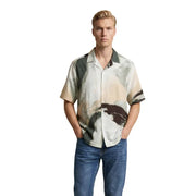 Un homme portant un Only & Sons Chemise boutonnée à manches courtes avec un motif pictural abstrait aux tons terreux