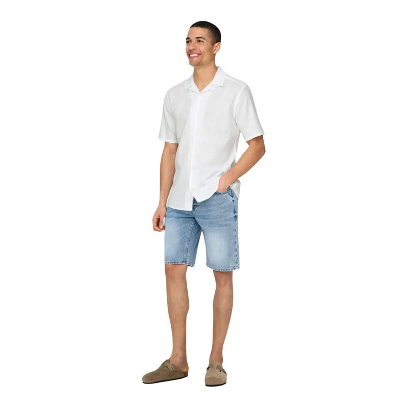 Un homme portant only Chemise de villégiature blanche en lin mélangé pour homme, short en jean délavé et chaussures slip-on en daim marron.