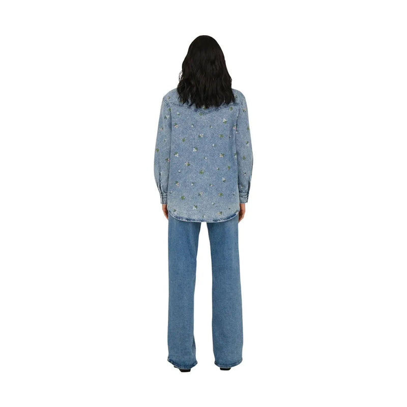 Back view of only women light blue cotton long denim shirt with subtle floral embroidery across the back