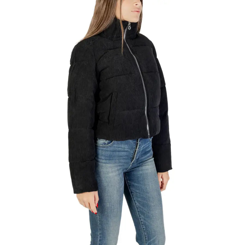 Women’s black puffer jacket with high collar and silver zipper over blue jeans