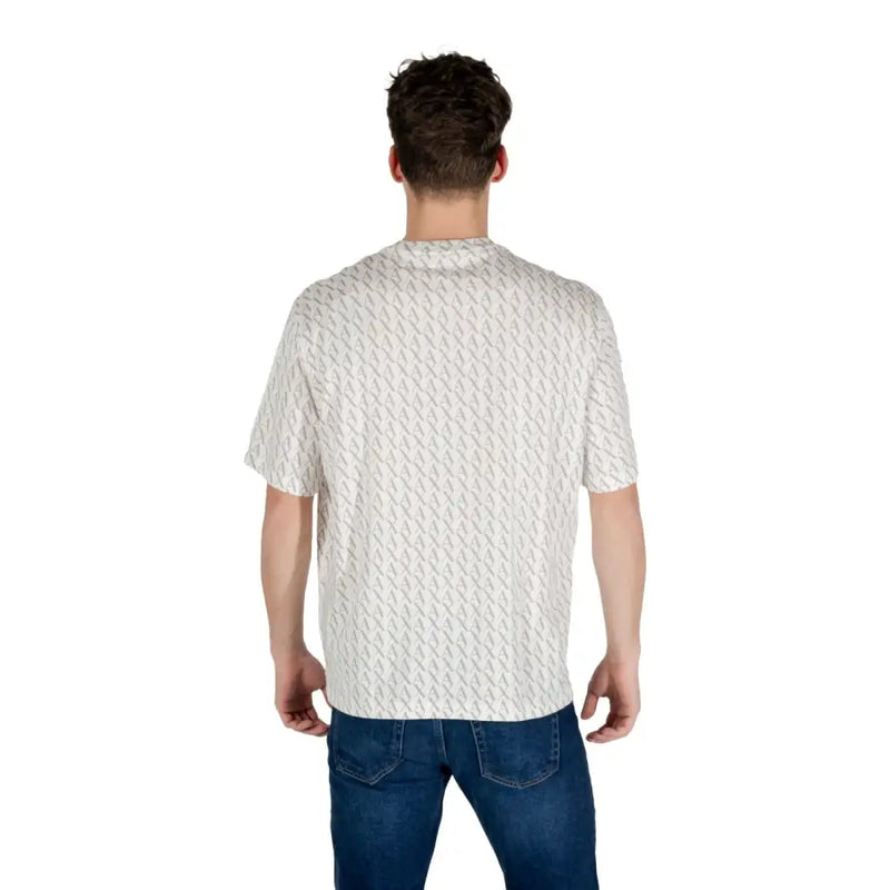 Un homme portant un t-shirt blanc à manches courtes à motifs géométriques gris clair discrets.