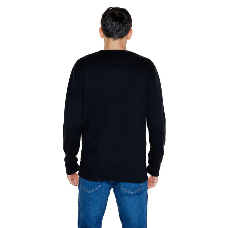 Person wearing a Black Long Sleeved Crewneck Sweater and Blue Jeans