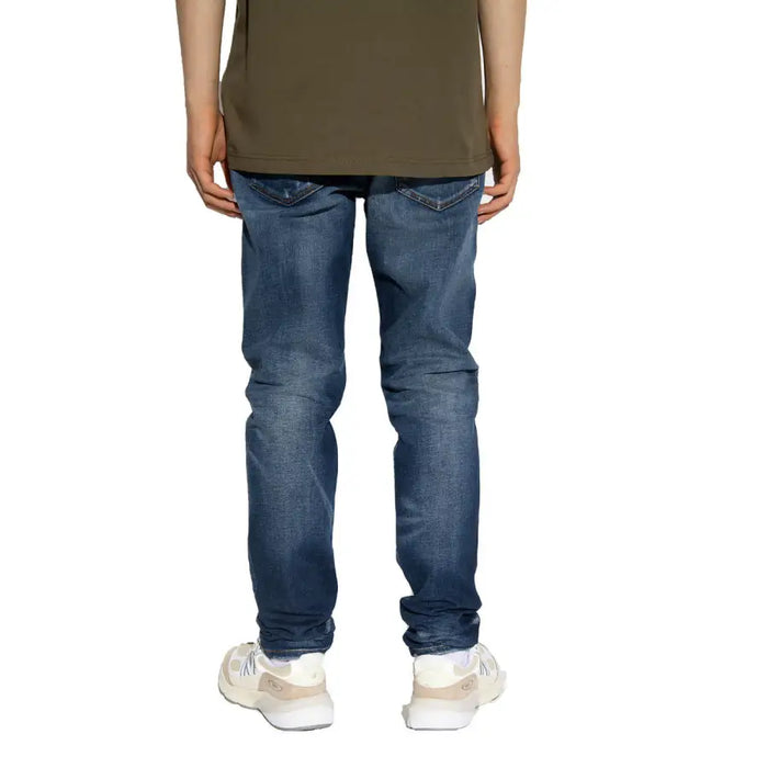 Model wearing distressed blue denim jeans and sneakers in a product display